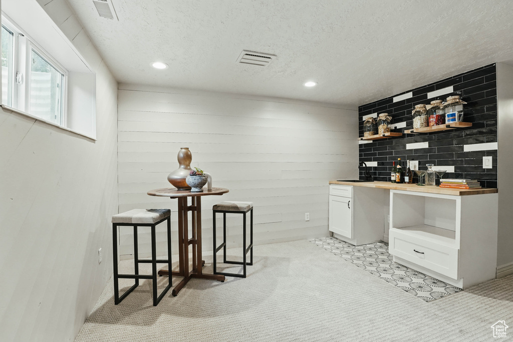 Bar area with a textured ceiling, light carpet, and recessed lighting