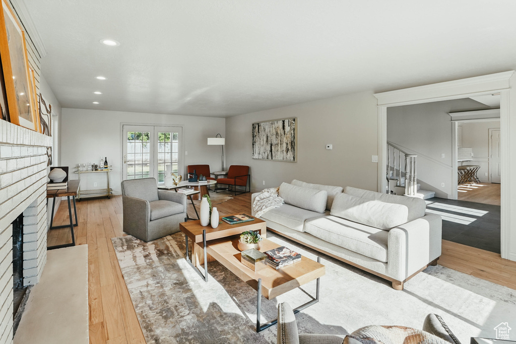 Living room with a fireplace, light wood finished floors, recessed lighting, and stairway
