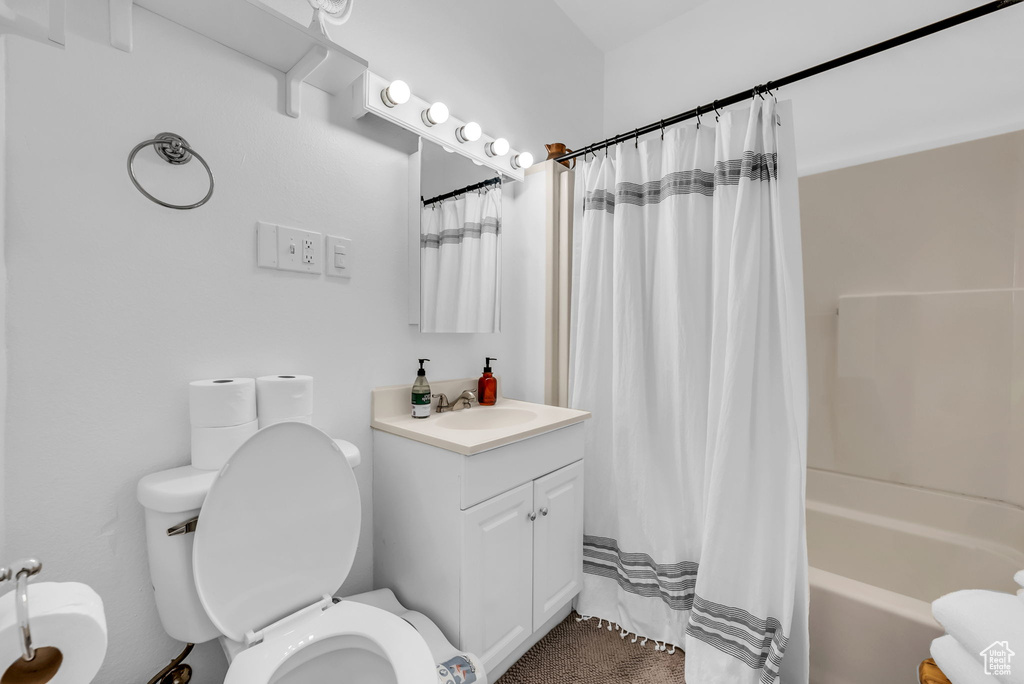 Bathroom featuring toilet, vanity, and shower / tub combo with curtain