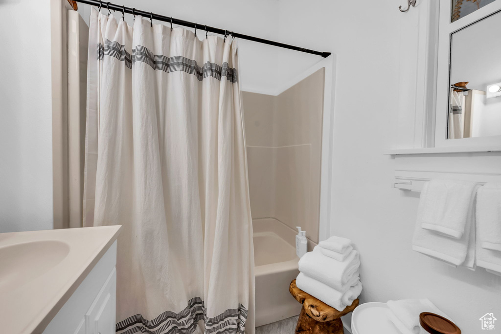 Bathroom with toilet, shower / bathtub combination with curtain, and vanity