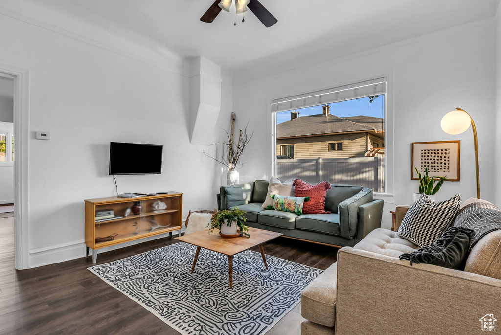 Living area with a ceiling fan, wood finished floors, and baseboards
