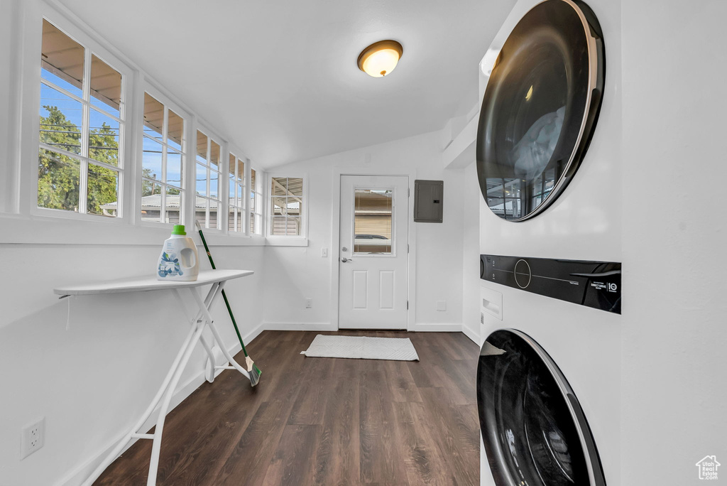 Laundry room with stacked washer / dryer, dark wood finished floors, baseboards, and electric panel