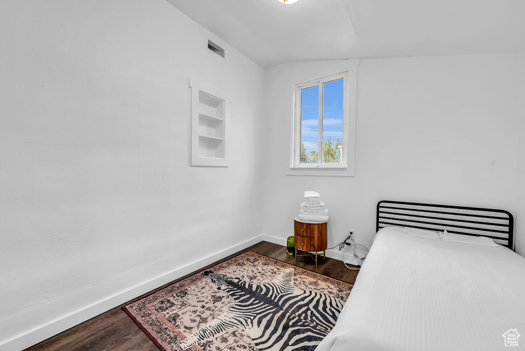 Bedroom featuring dark wood-style floors, baseboards, and vaulted ceiling