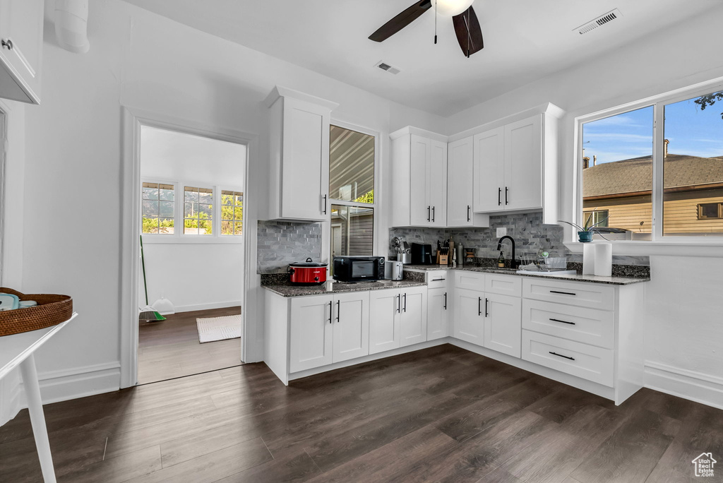 Kitchen featuring a ceiling fan, tasteful backsplash, dark wood-style floors, and dark stone counters