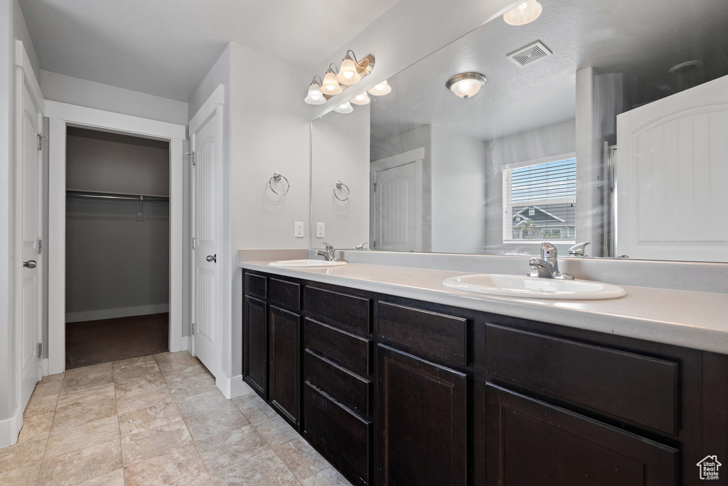 Bathroom with double vanity and a walk in closet