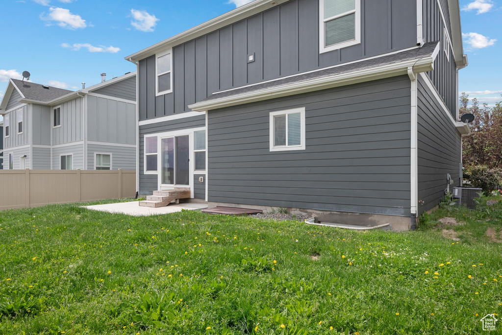 Rear view of house featuring board and batten siding, central AC unit, and a patio area