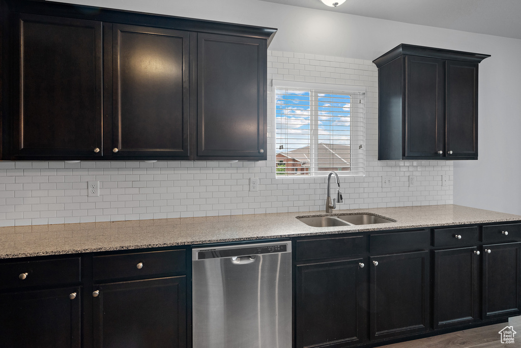 Kitchen with dishwasher, a sink, backsplash, and light stone counters