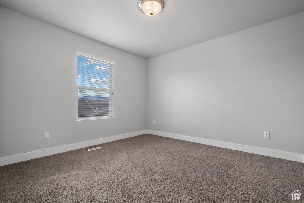 Carpeted empty room featuring baseboards
