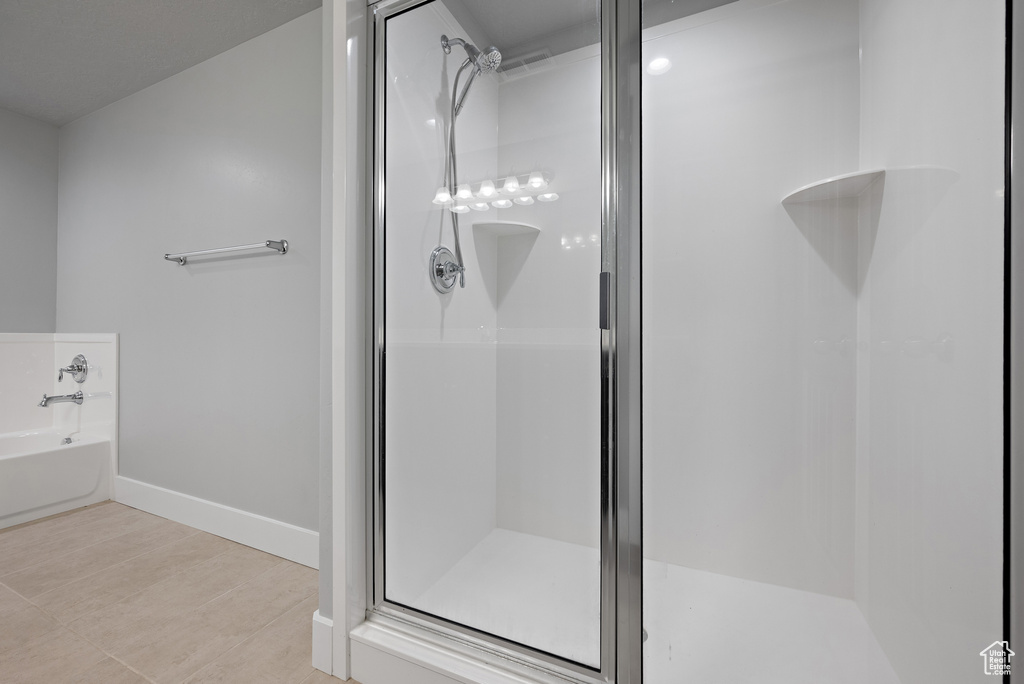 Full bath with a shower stall, a garden tub, and baseboards