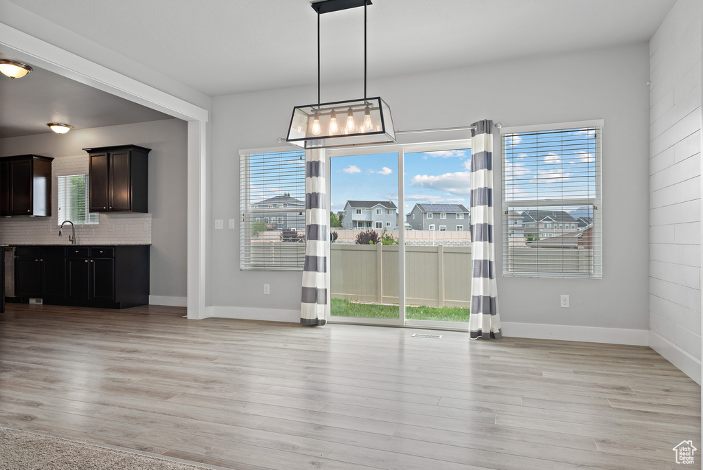 Unfurnished dining area featuring plenty of natural light, a sink, and light wood-style flooring