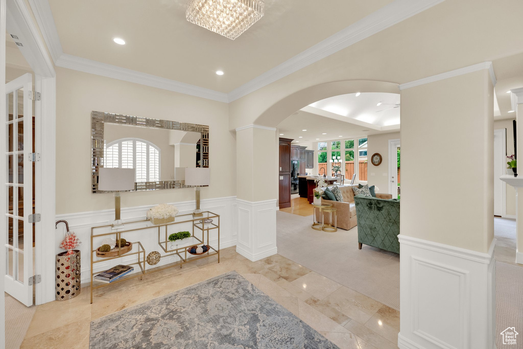 Entryway featuring arched walkways, recessed lighting, crown molding, and wainscoting