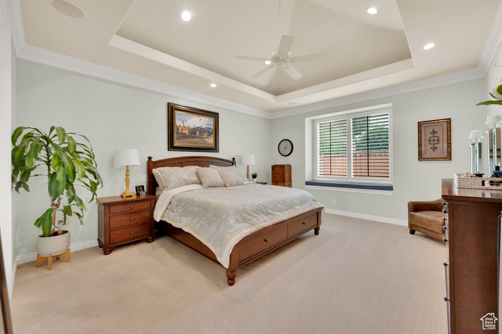 Bedroom featuring light carpet, a tray ceiling, baseboards, ornamental molding, and a ceiling fan