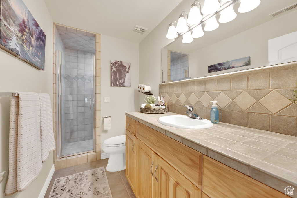Bathroom with toilet, vanity, a shower stall, tasteful backsplash, and tile patterned flooring