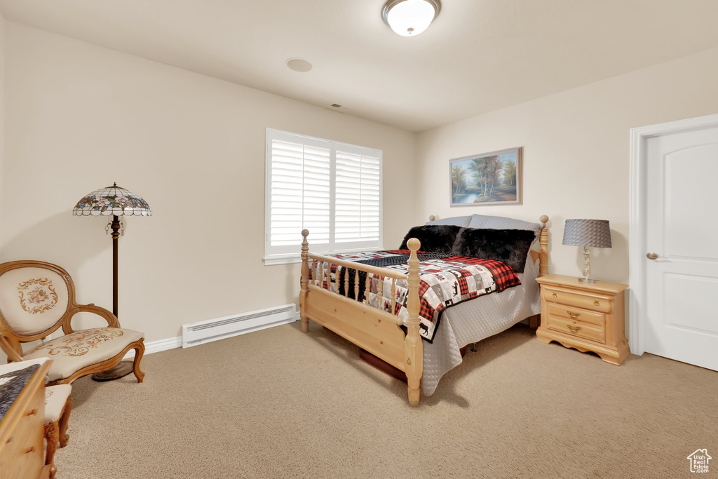 Bedroom featuring baseboard heating, light carpet, and baseboards