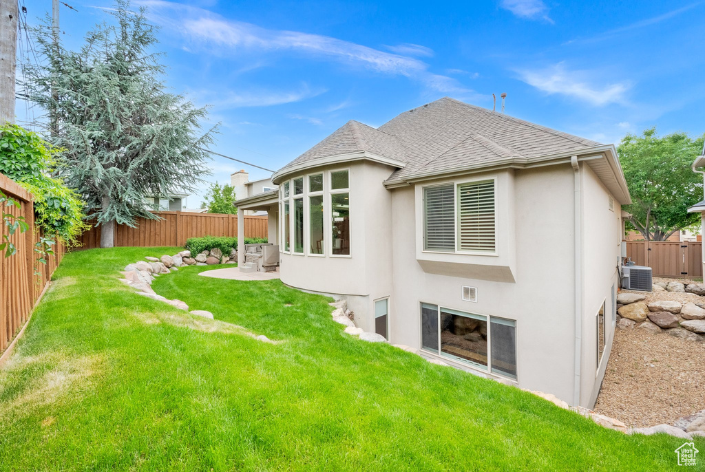 Rear view of property with stucco siding, central AC, a shingled roof, and a patio
