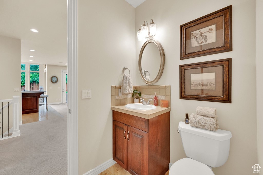 Bathroom featuring vanity, backsplash, toilet, recessed lighting, and baseboards
