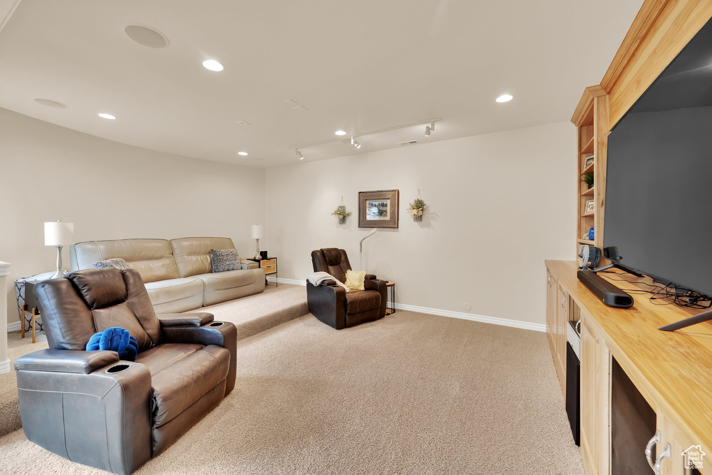 Living area with light colored carpet, baseboards, and recessed lighting