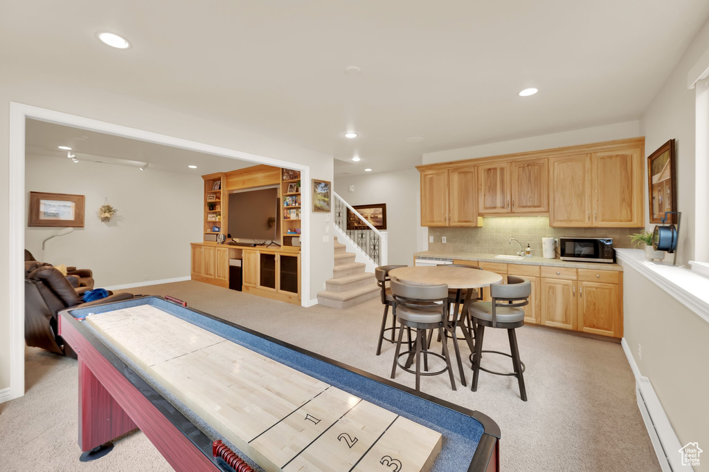 Kitchen with light brown cabinetry, light colored carpet, light countertops, decorative backsplash, and recessed lighting