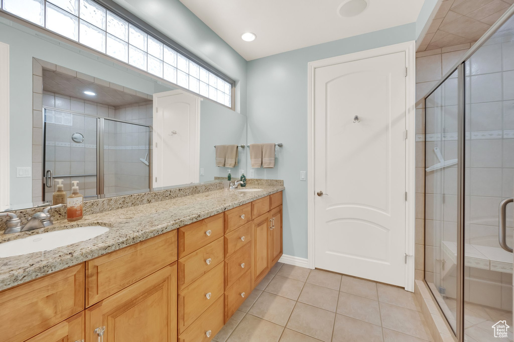 Bathroom with double vanity, a shower stall, tile patterned floors, and baseboards