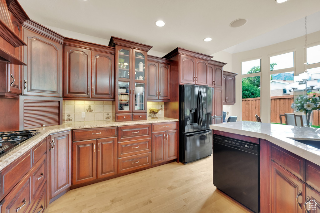 Kitchen with black appliances, light wood-style flooring, recessed lighting, backsplash, and hanging light fixtures