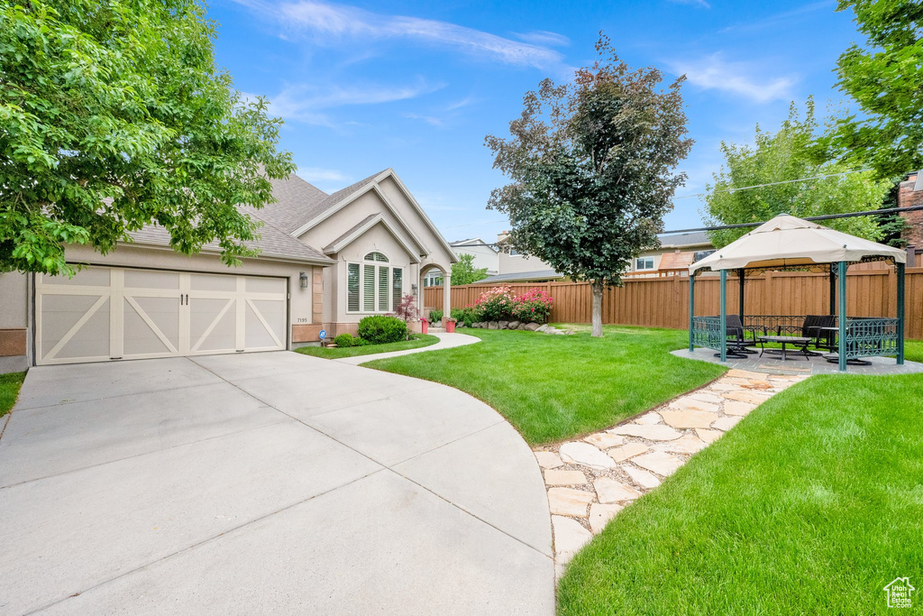 View of front of house with a gazebo, concrete driveway, stucco siding, a garage, and a shingled roof