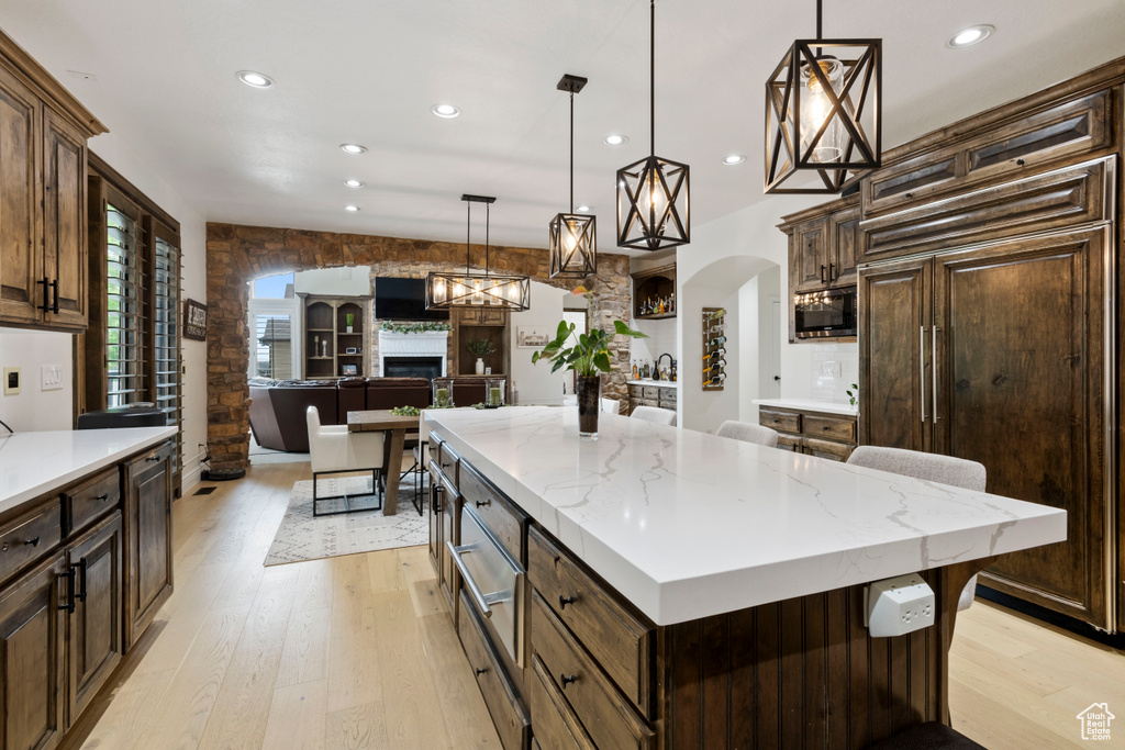 Kitchen with stainless steel microwave, paneled built in refrigerator, recessed lighting, light wood-style floors, and arched walkways