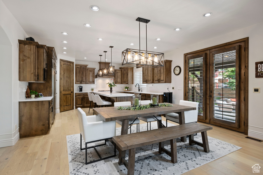 Dining area with a chandelier, recessed lighting, light wood-style floors, and baseboards