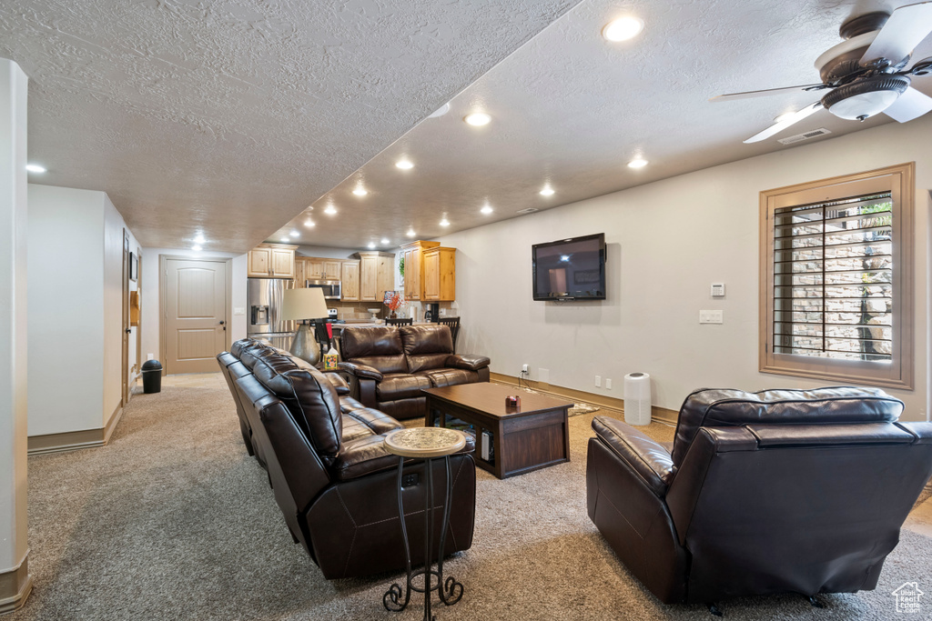 Living area featuring a textured ceiling, recessed lighting, light carpet, ceiling fan, and baseboards