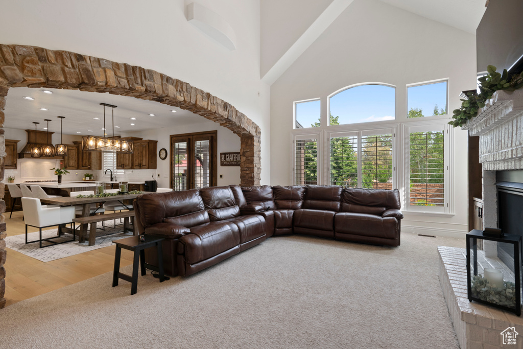Living room with high vaulted ceiling, light carpet, a chandelier, recessed lighting, and a fireplace
