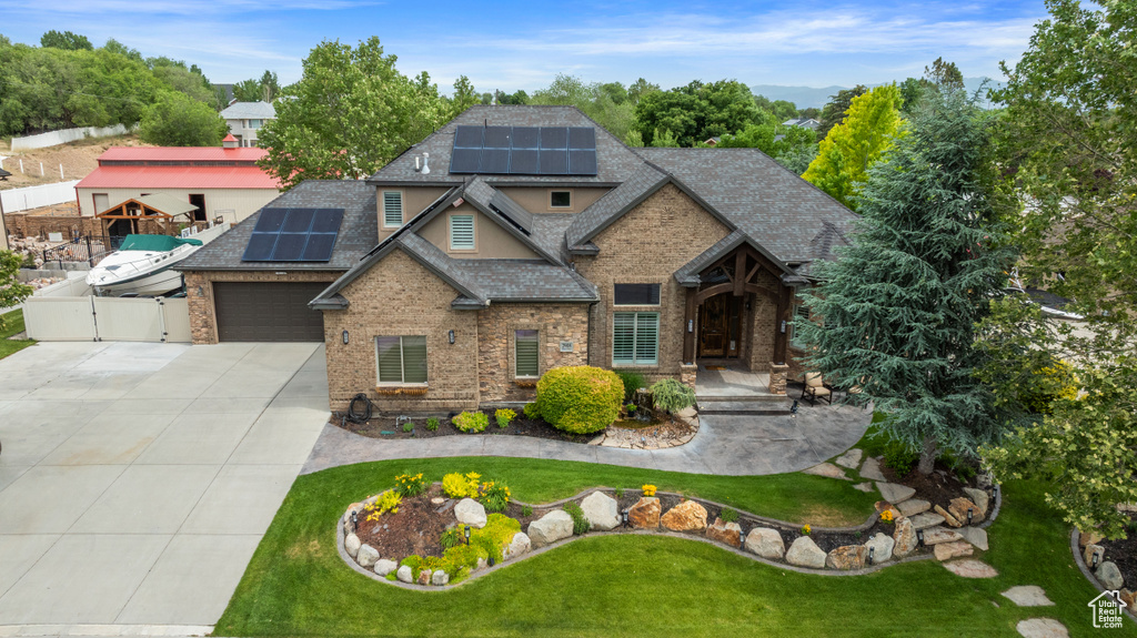 Craftsman-style house featuring concrete driveway, a shingled roof, a gate, and solar panels