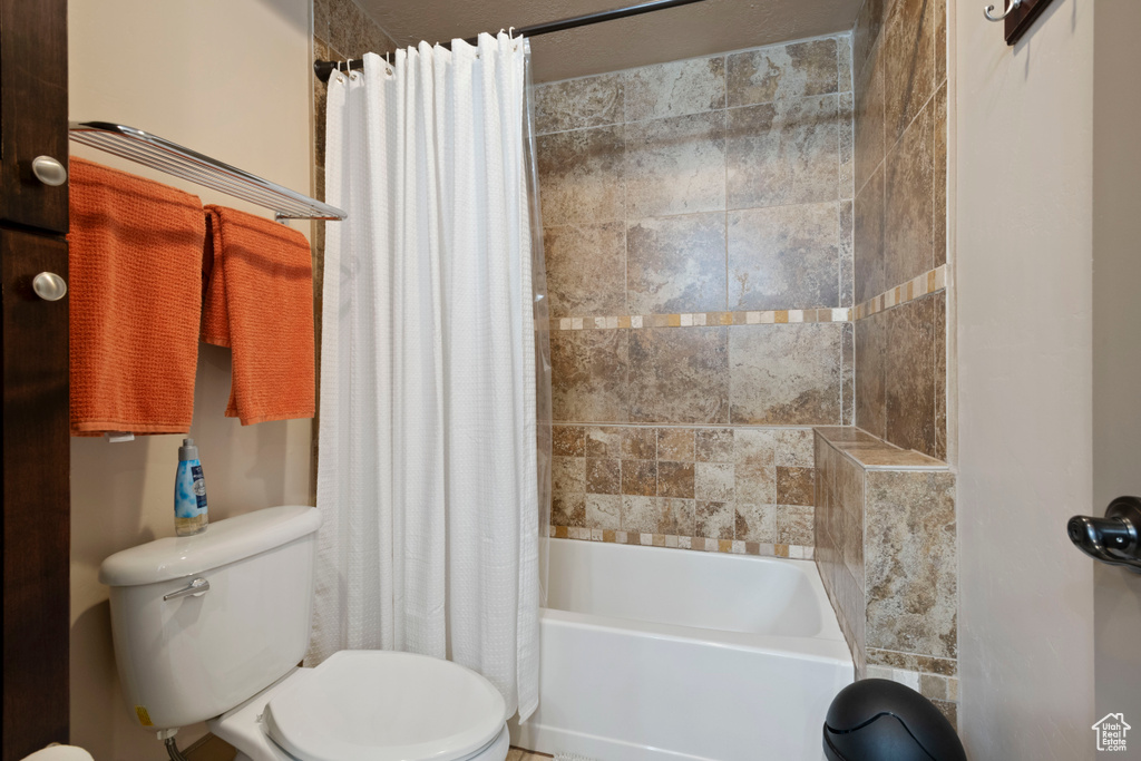 Full bath featuring toilet and shower / tub combo with curtain