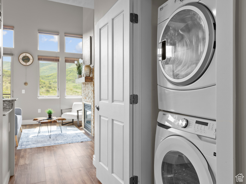 Laundry area featuring estacked washer and dryer, wood finished floors, and baseboards