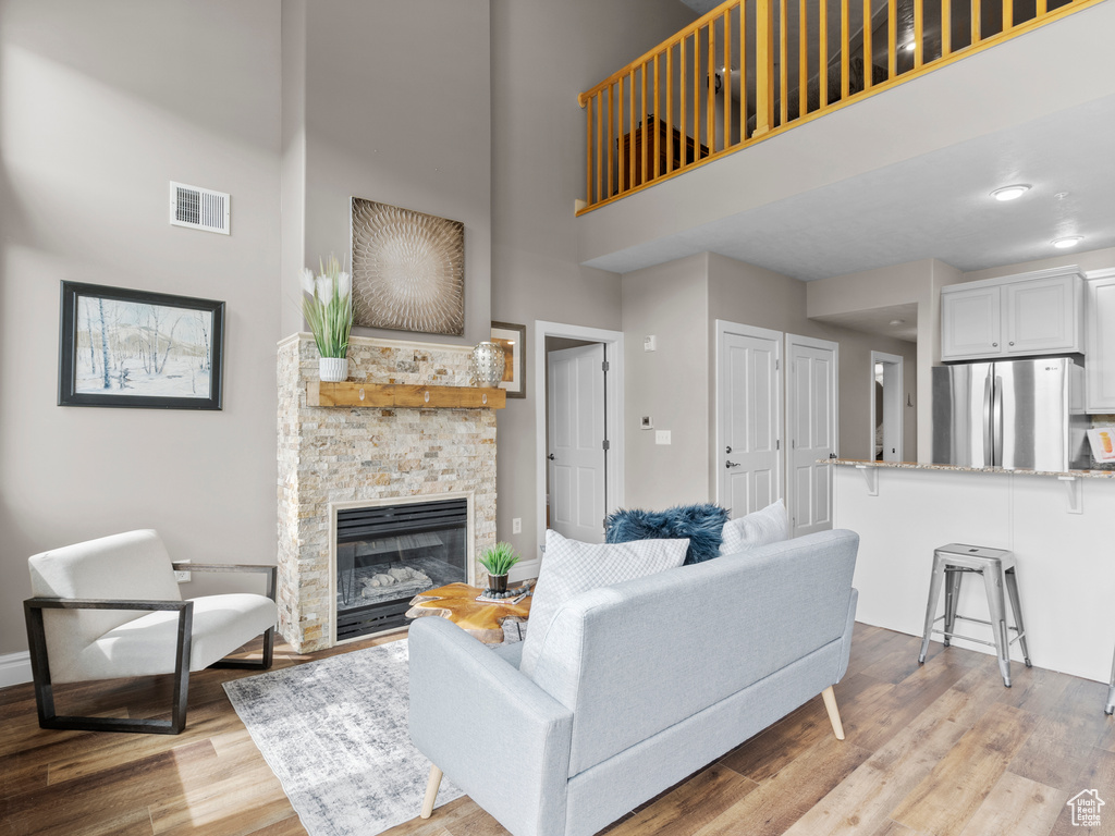 Living room with a high ceiling, light wood-type flooring, a fireplace, and baseboards