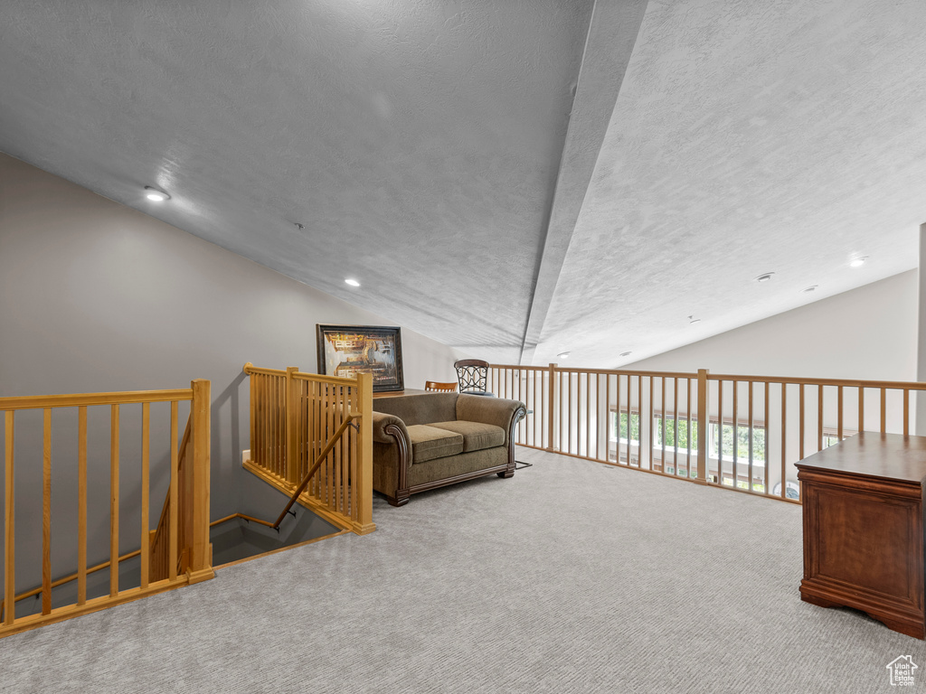 Sitting room with vaulted ceiling, carpet flooring, a textured ceiling, an upstairs landing, and recessed lighting