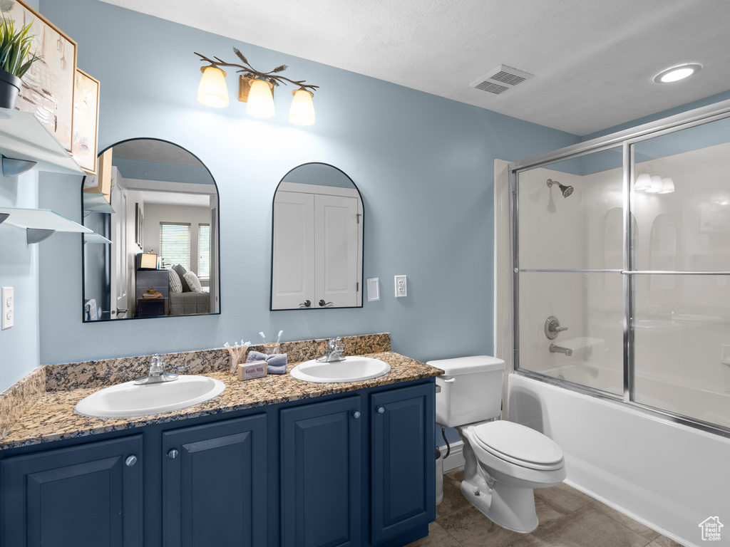 Ensuite bathroom with double vanity, toilet, shower / bath combination with glass door, and tile patterned floors