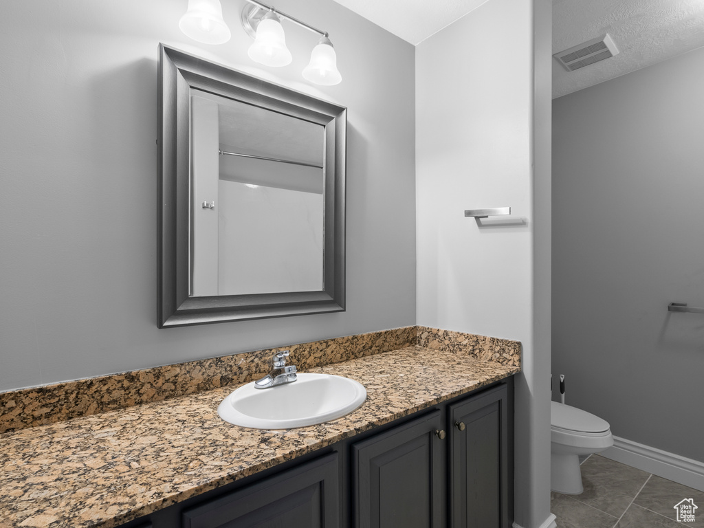 Bathroom featuring vanity, toilet, and baseboards