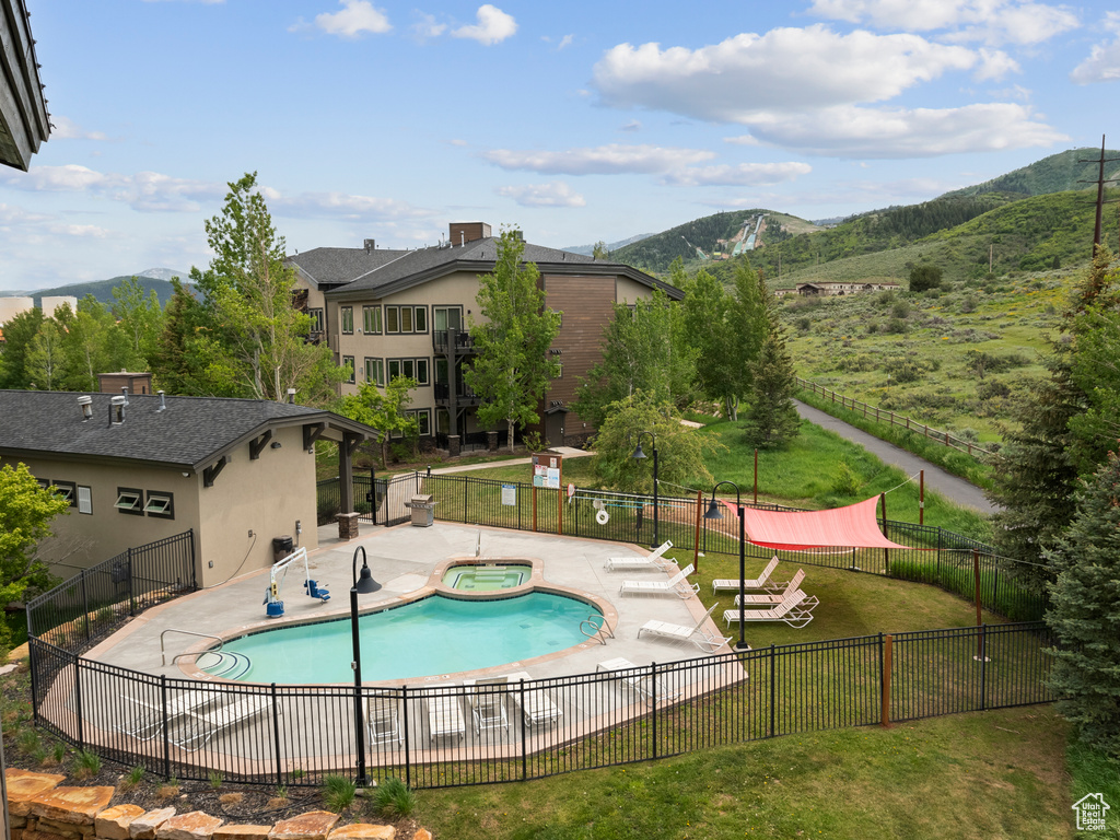 Community pool featuring a hot tub, a mountain view, and a patio area