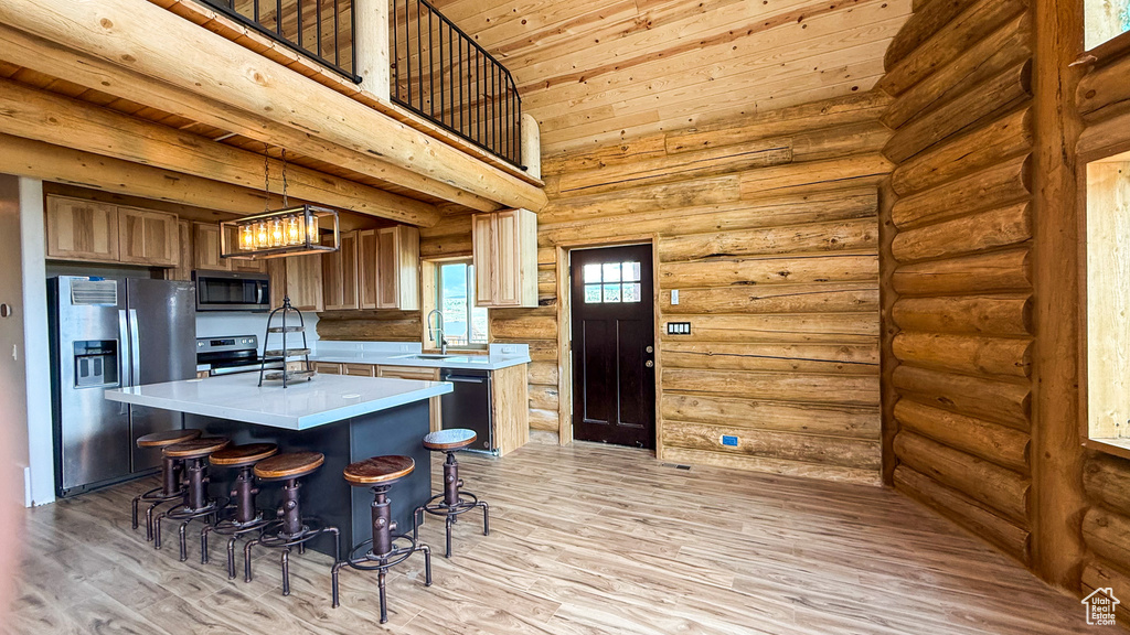 Kitchen featuring appliances with stainless steel finishes, light countertops, a kitchen island, rustic walls, and wooden ceiling