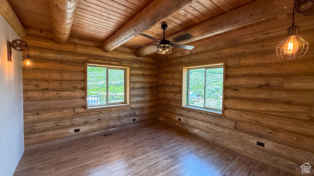 Unfurnished room with wood ceiling with exposed beams, wood finished floors, ceiling fan, and log walls