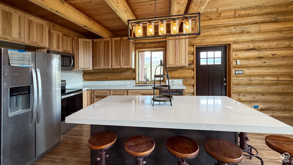 Kitchen featuring stainless steel appliances, log walls, wood ceiling with exposed beams, a sink, and light countertops