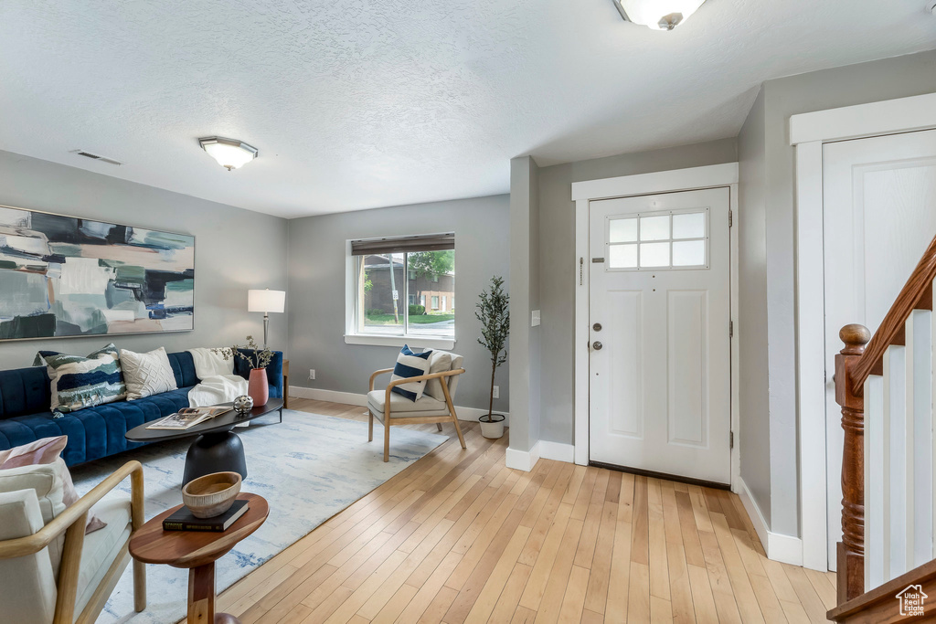 Entryway featuring healthy amount of natural light, baseboards, light wood finished floors, and a textured ceiling