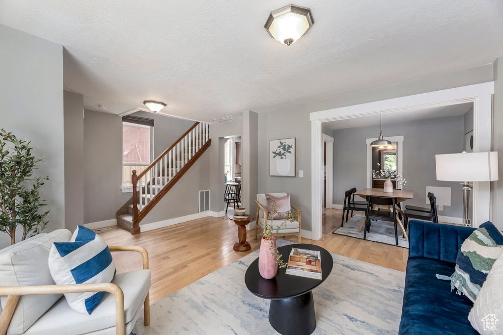 Living area with wood finished floors, stairway, healthy amount of natural light, baseboards, and a textured ceiling
