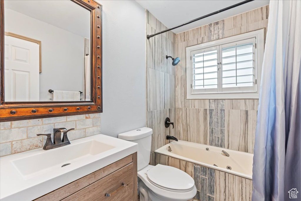 Full bath with tiled shower / bath combo, toilet, vanity, and backsplash