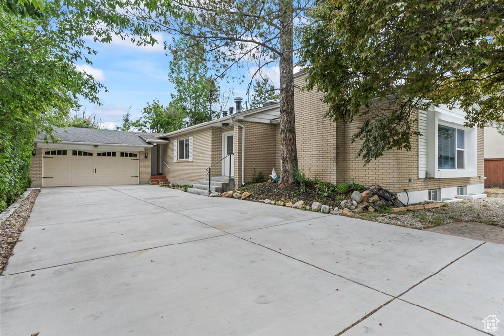View of front of home featuring concrete driveway, brick siding, and a garage