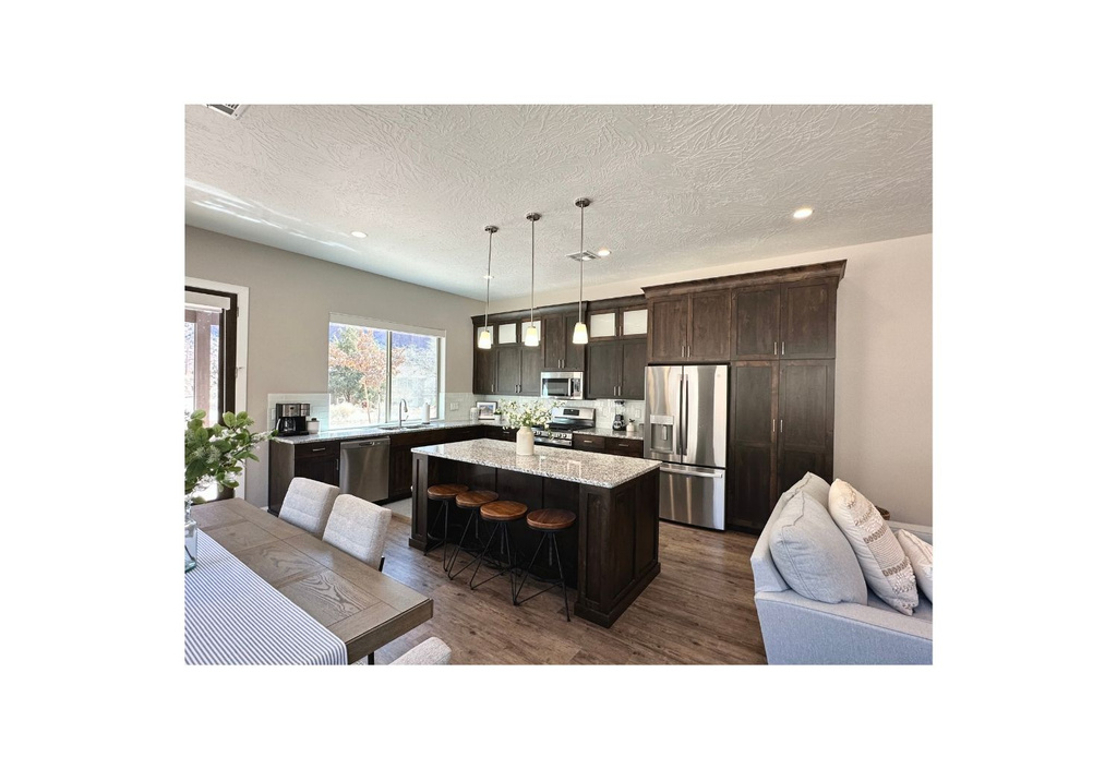 Kitchen featuring appliances with stainless steel finishes, a sink, a kitchen island, a kitchen breakfast bar, and dark brown cabinets