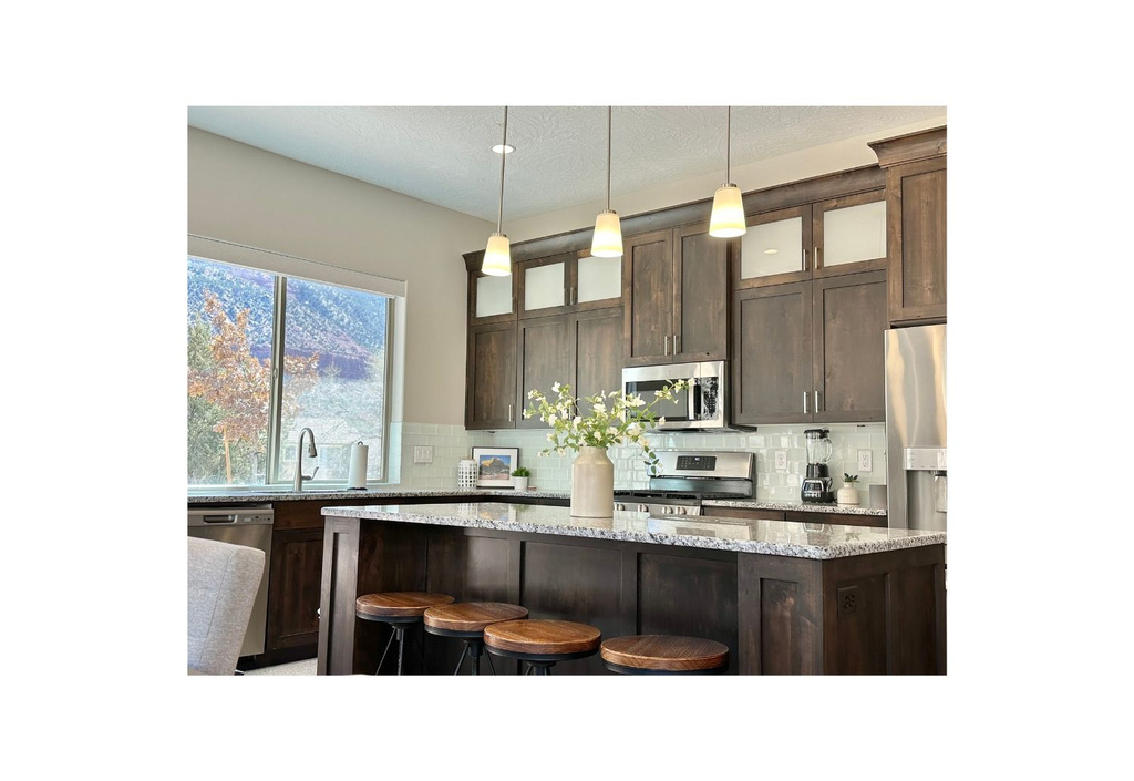 Kitchen featuring appliances with stainless steel finishes, dark brown cabinets, and decorative backsplash