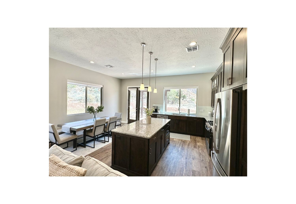 Kitchen with freestanding refrigerator, a kitchen island, a textured ceiling, light wood-style flooring, and recessed lighting