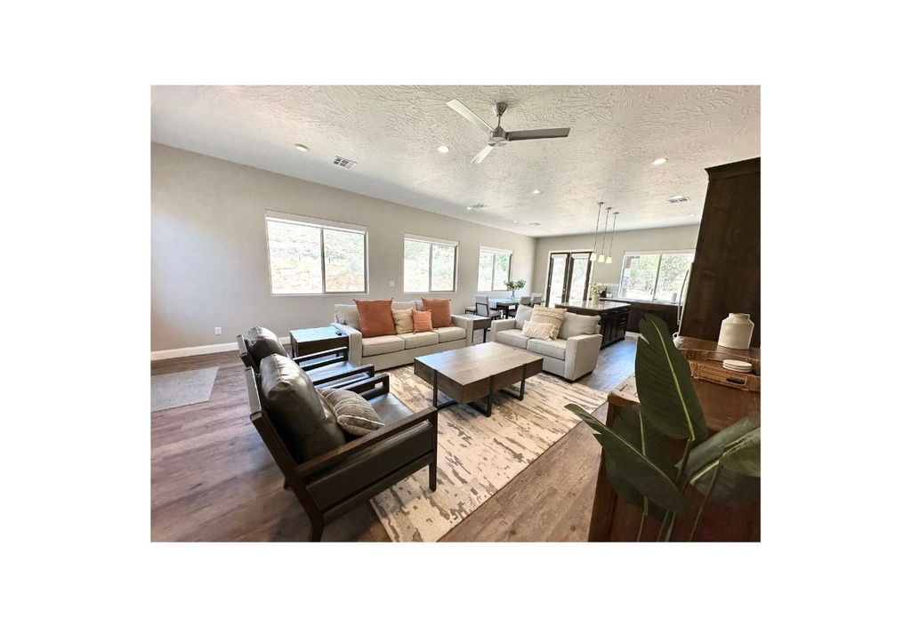 Living area featuring wood finished floors, a ceiling fan, a textured ceiling, recessed lighting, and baseboards