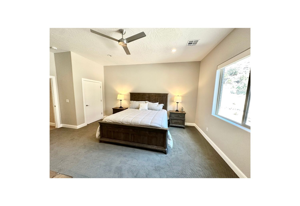 Bedroom with dark carpet, baseboards, ceiling fan, and a textured ceiling