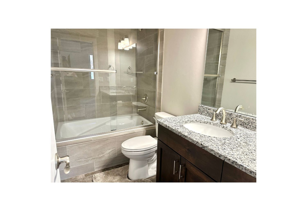 Full bathroom with toilet, combined bath / shower with glass door, vanity, and tile patterned flooring